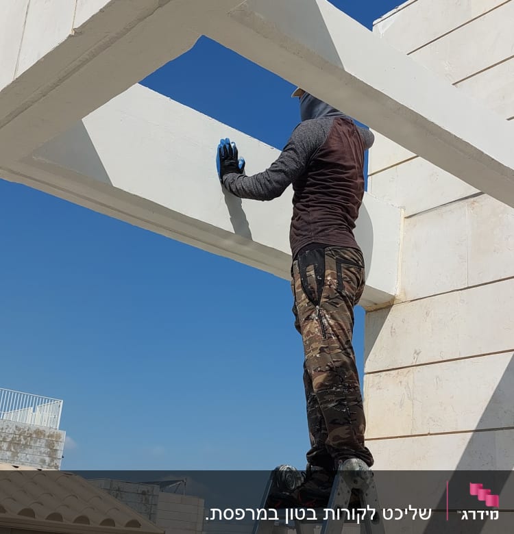 אדם על סולם צובע קורה לבנה